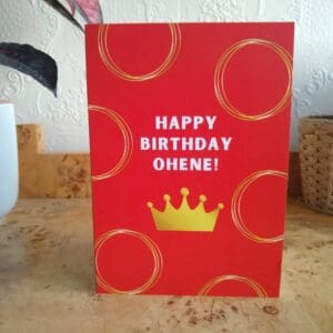 Happy Birthday Ohene written in gold on a red background with a gold crown underneath and gold circles all over the card